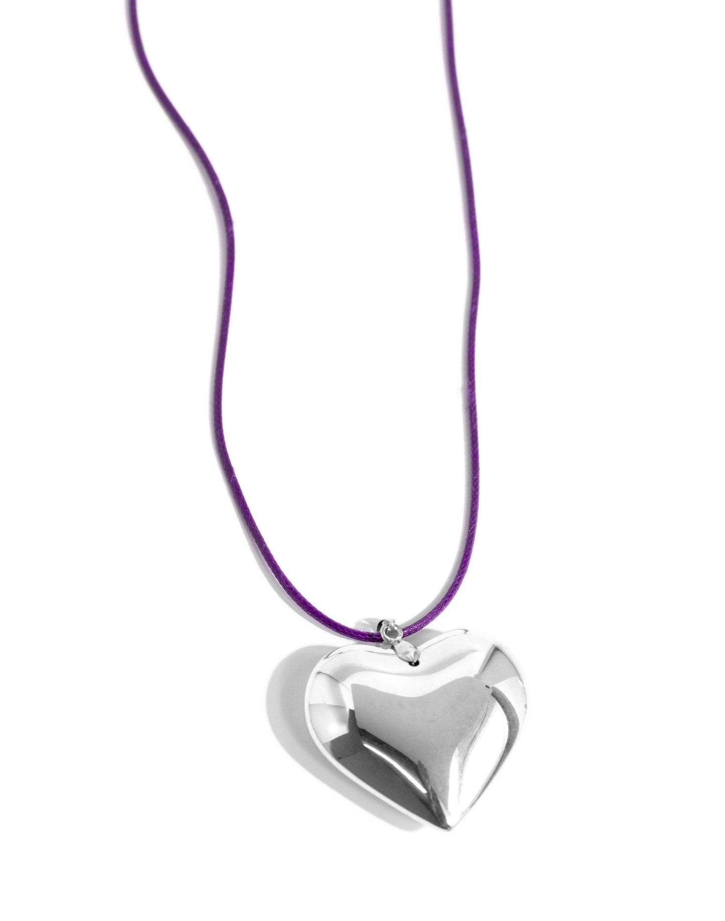 An oversized, sleek silver heart glides along a vibrant purple cord, creating a flirtatious pendant below the collar. Features an adjustable clasp closure.
N3305