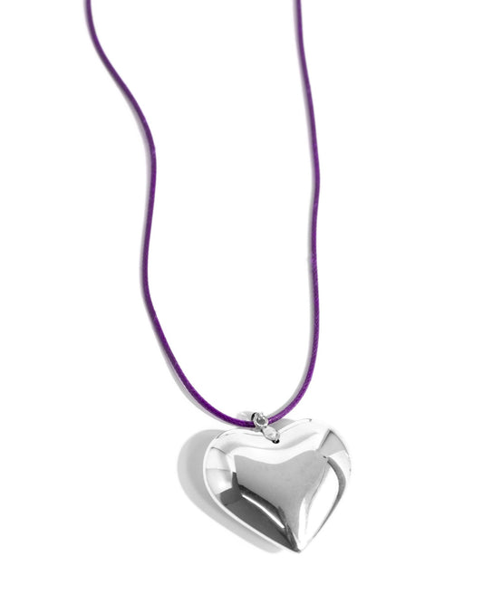 An oversized, sleek silver heart glides along a vibrant purple cord, creating a flirtatious pendant below the collar. Features an adjustable clasp closure.
N3305